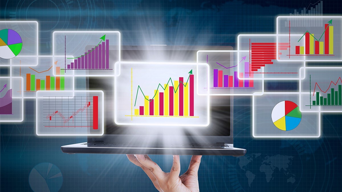 A hand holds a laptop with colorful bar and pie charts depicting sales enablement metrics, emerging from the screen. These are surrounded by floating chart imagery and a digital grid background, symbolizing data analysis and business growth.